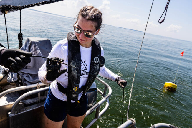A woman on a research vessel hauls in hypoxia monitoring equipment.