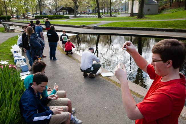 Students from a club test water in a man-made stream outside