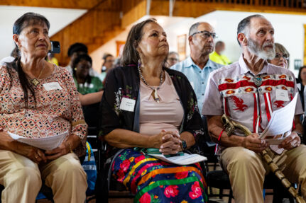 Three members of the Rappahannock Tribe listen intently, watching the speaker during the celebration.