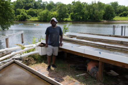 Man stands in front of Algal Turf Scubber along the Anacostia River.