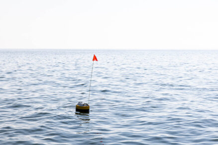 A high-tech buoy with a red flag on top floats in the water.