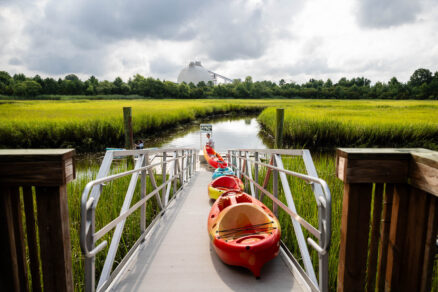 Staff member lines up kayaks on the floating kayak launch near the restored marsh.