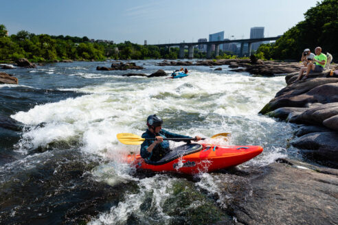 Kayakers paddle through rapids on the James River in Richmond, Virginia.