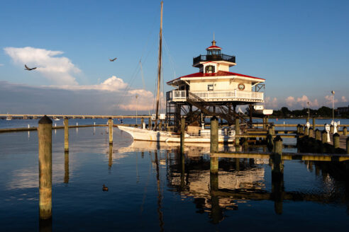 A short lighthouse screwed to a platform in the water.