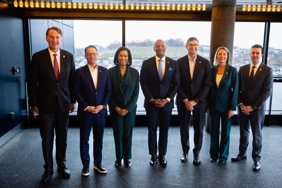 A group of people stand in a line in front of a large window.