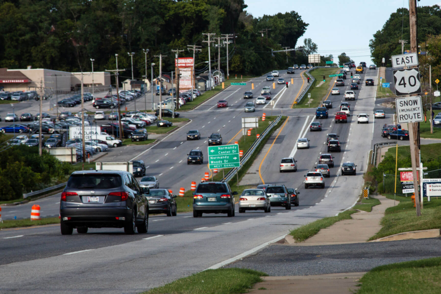 Cars drive along a suburban roadway that is home to car dealerships, shopping centers and other retailers.