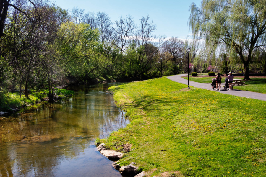 Linville Creek flows on the left side with a grassy area and paved walking trail on the right.