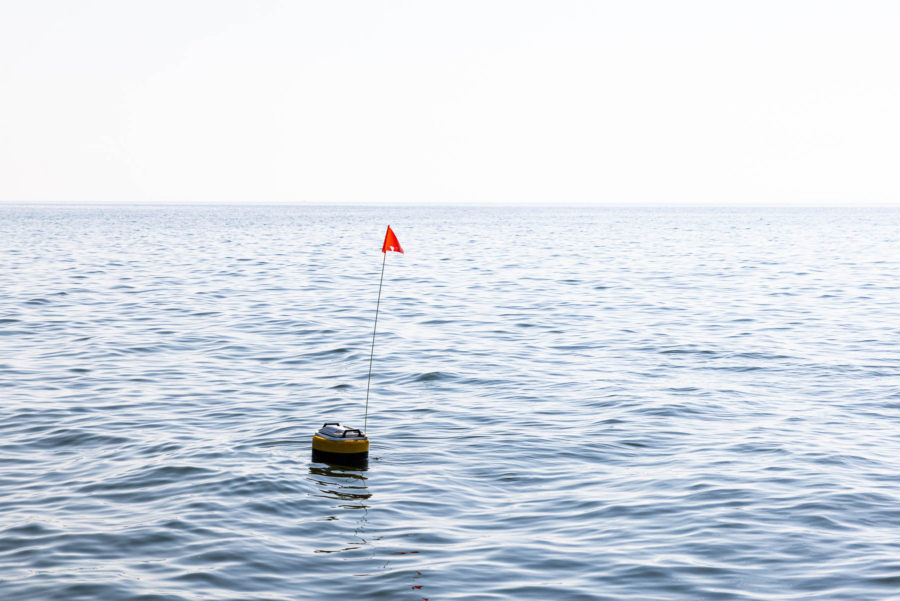 A high-tech buoy with a red flag on top floats in the water.