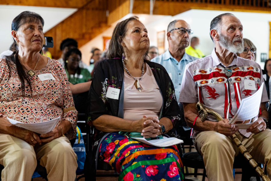 A seated crowd of tribe members and supporters pays close attention to a speaker's remarks.
