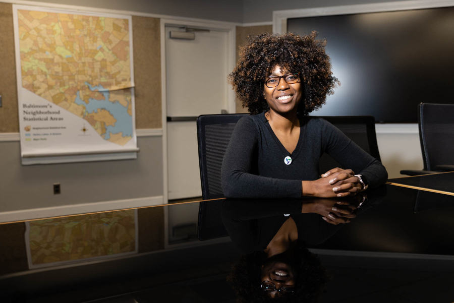 Ava poses in an office room with a map of Baltimore in the background.