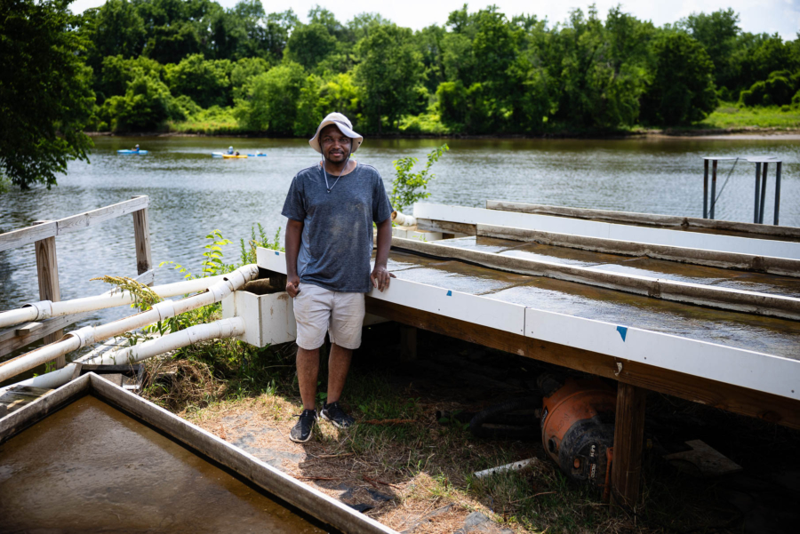 Larry Davis stands amid PVC pips and other equipment on a bank overlooking the Anacostia River.