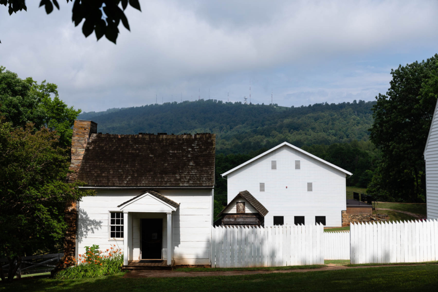 A historic white building with a dark roof in front of the Blue Ridge Mountains.