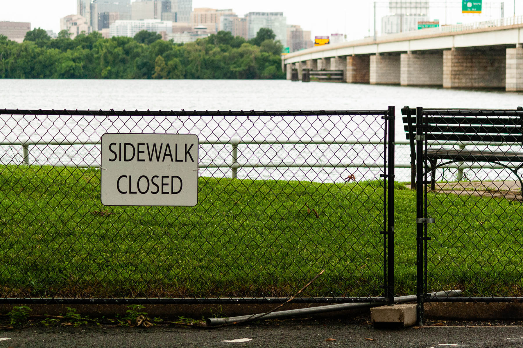 a fence with a sign reading sidewalk closed blocks of a section of park along the Potomac River