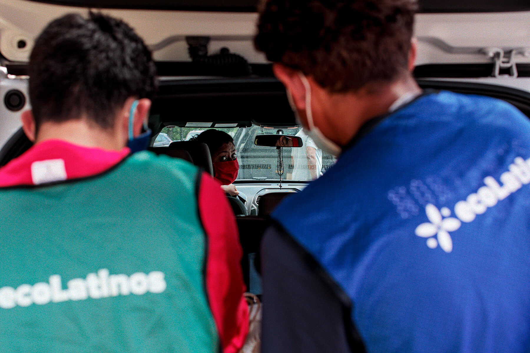ecoLatinos volunteer put groceries into a family's van.