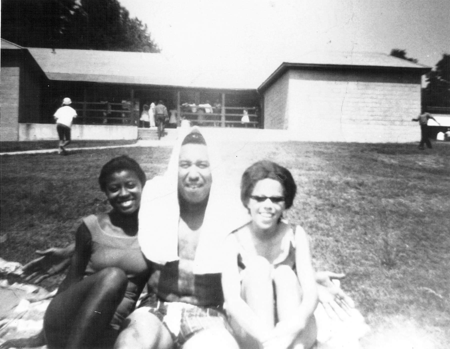 Three park visitors pose in the lawn wearing bathing suits.