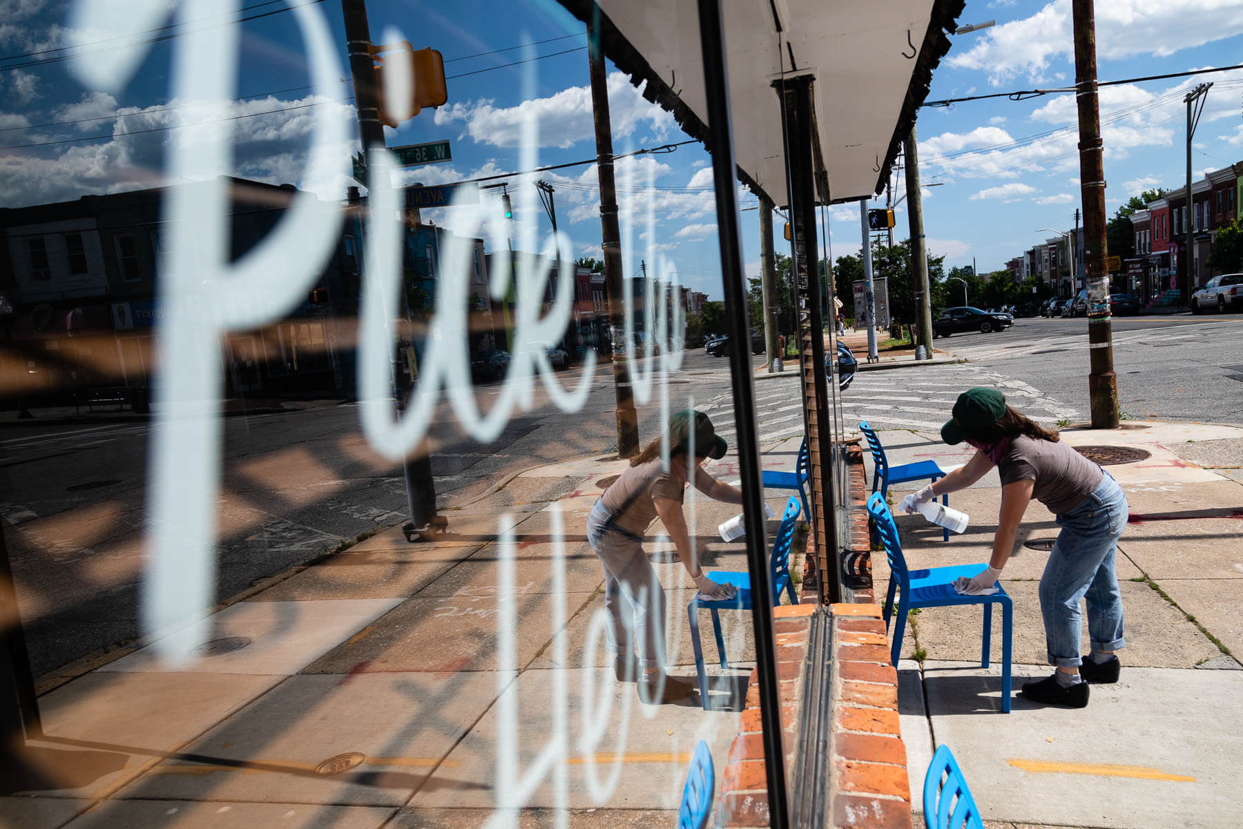A person wipes down a chair in front of an empty restaurant window